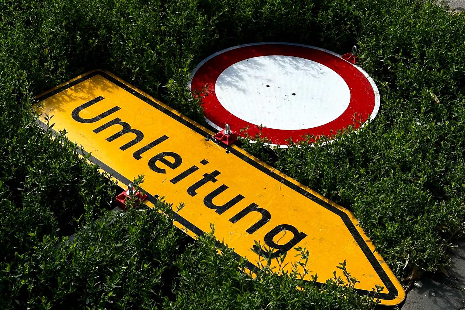 Umgekipptes Umleitungsschild, das im Gebüsch am Straßenrand liegt