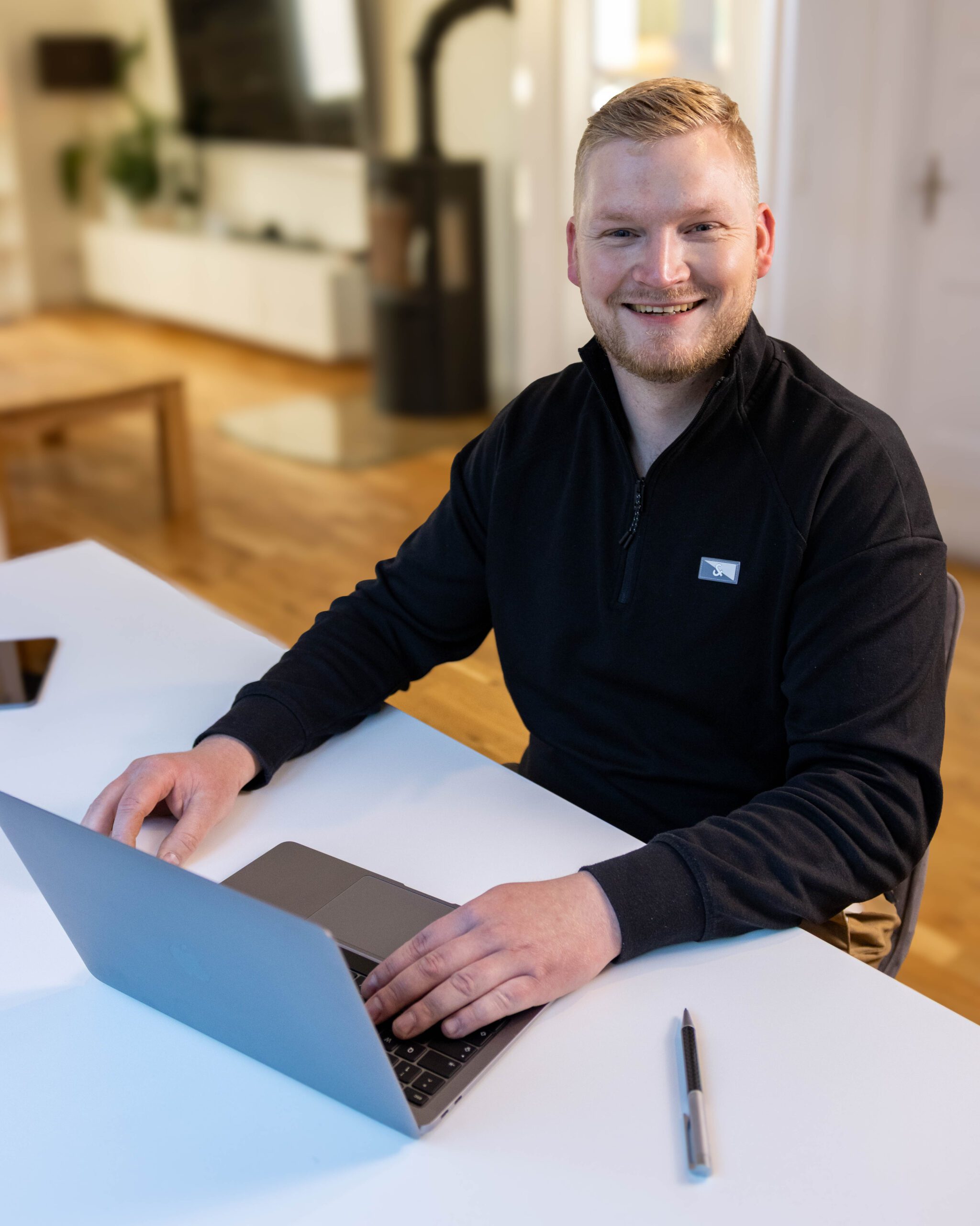 Raoul Steenken von Funkenart arbeitet an einem Laptop im Office und lächelt in die Kamera