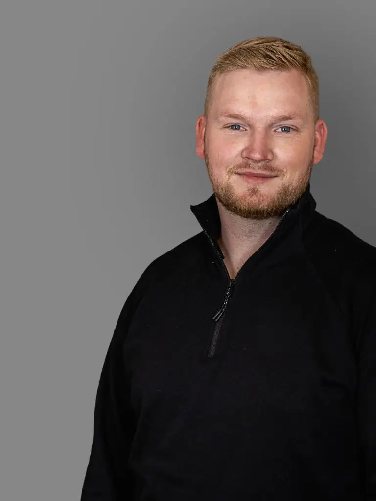 Raoul Steenken, Webdesigner steht vor grauem Hintergrund und lächelt in die Kamera